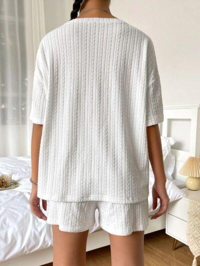 a woman standing in front of a bed wearing a white sweater and shorts