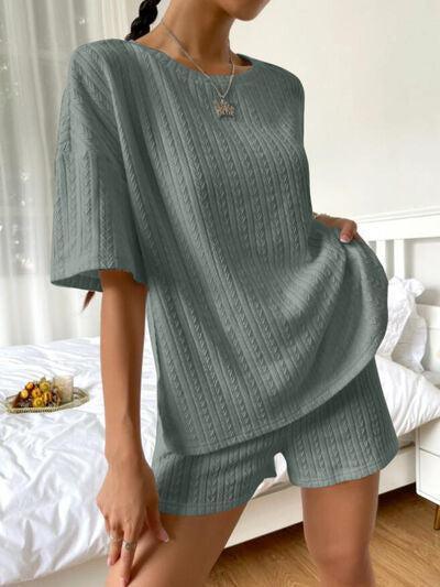 a woman standing in a bedroom wearing a green sweater and shorts