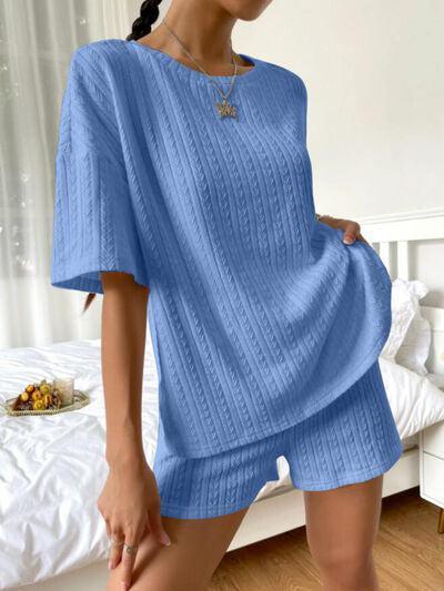 a woman standing in a bedroom wearing a blue sweater and shorts