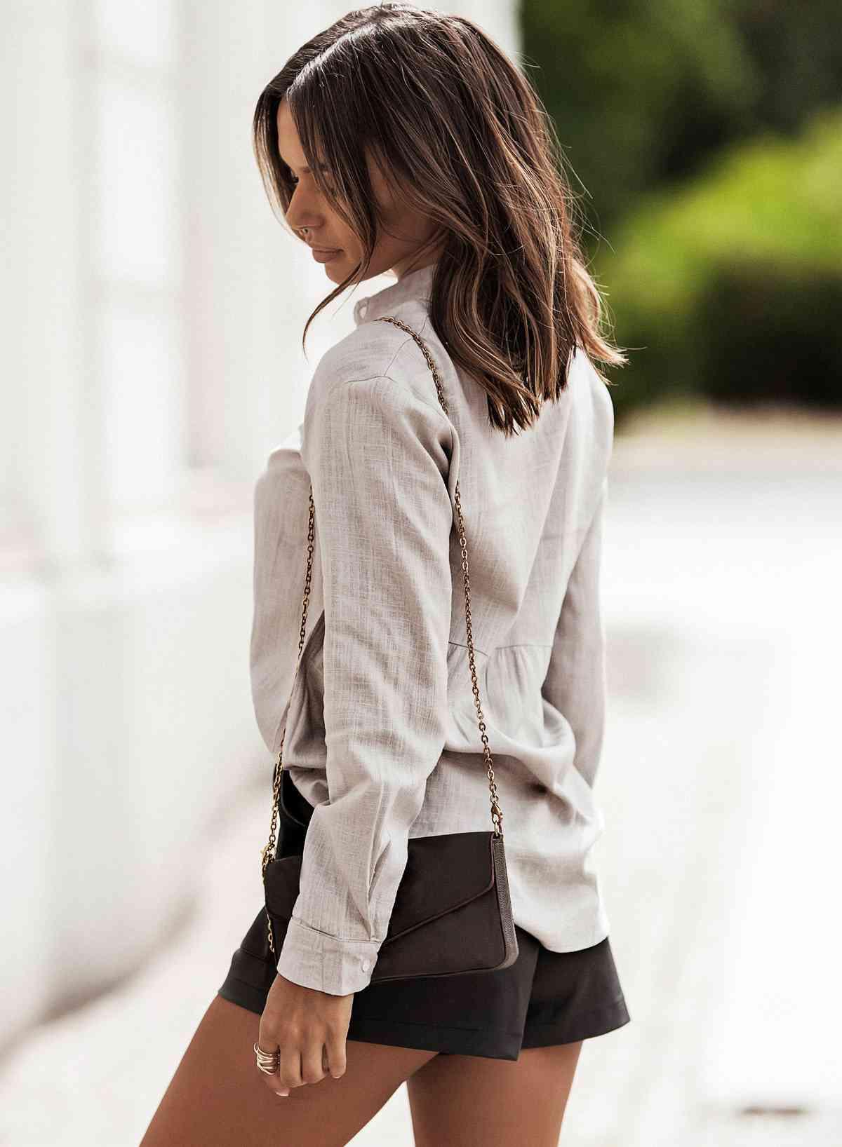 a woman walking down the street wearing a skirt and blazer