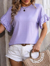 a woman wearing a purple top and white shorts