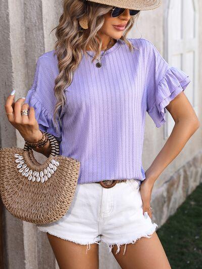 a woman wearing a purple top and white shorts