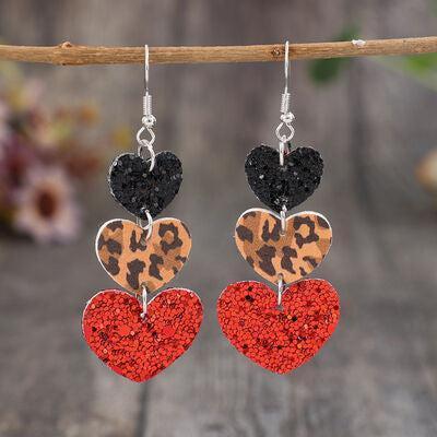 a pair of heart shaped earrings hanging from a branch