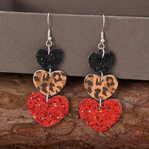 a pair of heart shaped earrings on a piece of wood