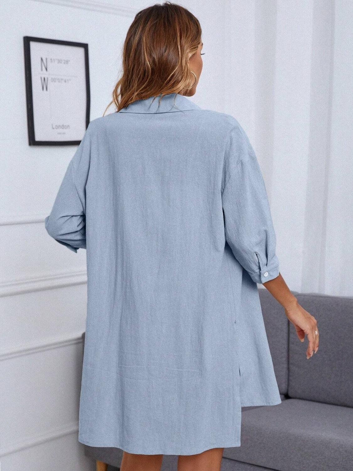 a woman standing in front of a couch wearing a blue shirt dress
