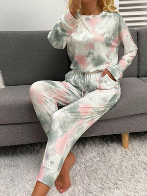 a woman sitting on a couch wearing a tie dye pajama set