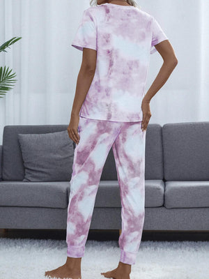 a woman standing in a living room wearing a pink and white tie dye pajamas