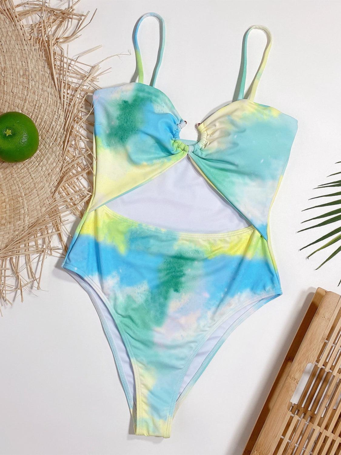 a tie - dyed one piece swimsuit sits on a table next to a green