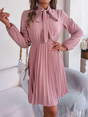 a woman wearing a pink pleated dress