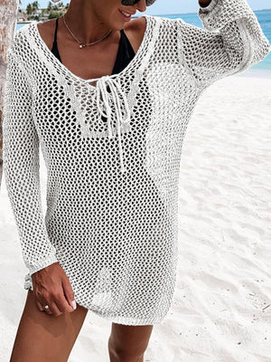 a woman standing on a beach wearing a white sweater