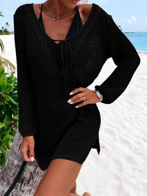 a woman standing on a beach wearing a black dress