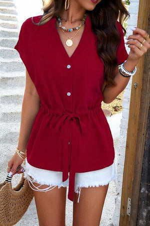 a woman wearing a red shirt and white shorts