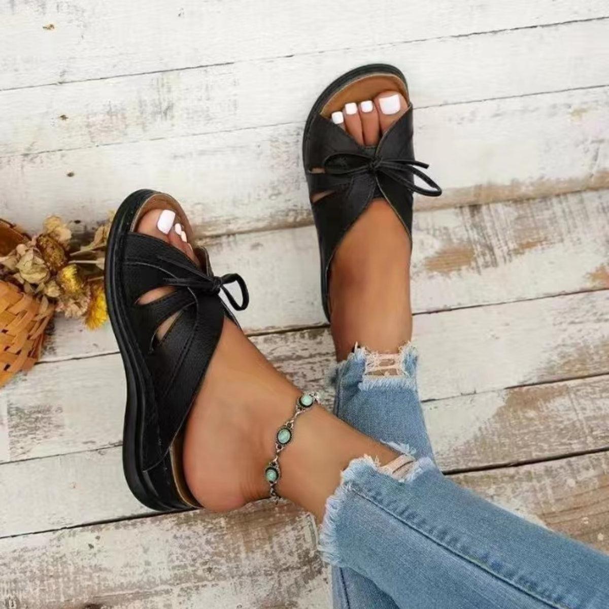 a woman's feet wearing black sandals and jeans
