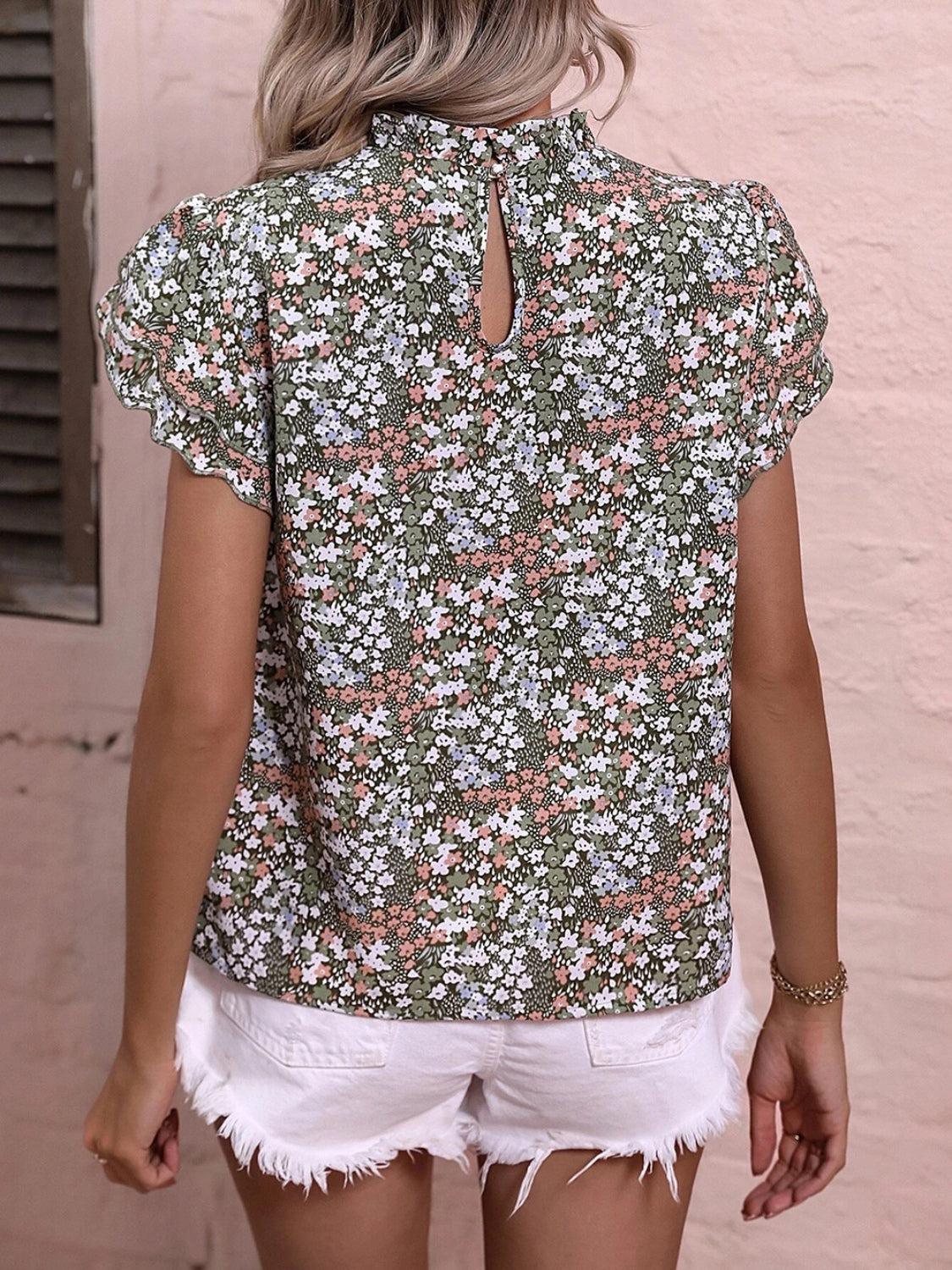 a woman wearing a floral blouse and white shorts