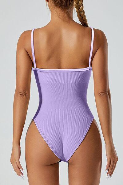 a woman in a purple swimsuit with her back to the camera
