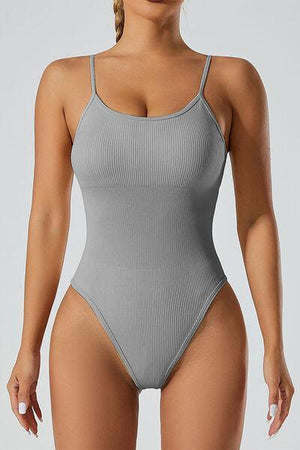 a woman in a gray bodysuit posing for the camera