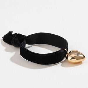 a black velvet bracelet with a gold heart charm