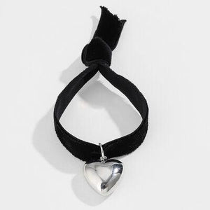 a heart shaped pendant hanging from a black cord