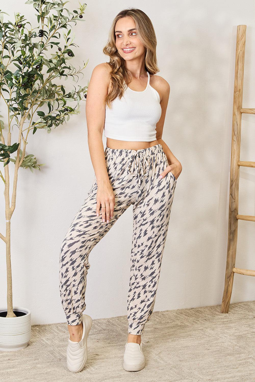 a woman in a white tank top and patterned pants