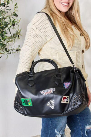 a woman holding a black handbag with stickers on it