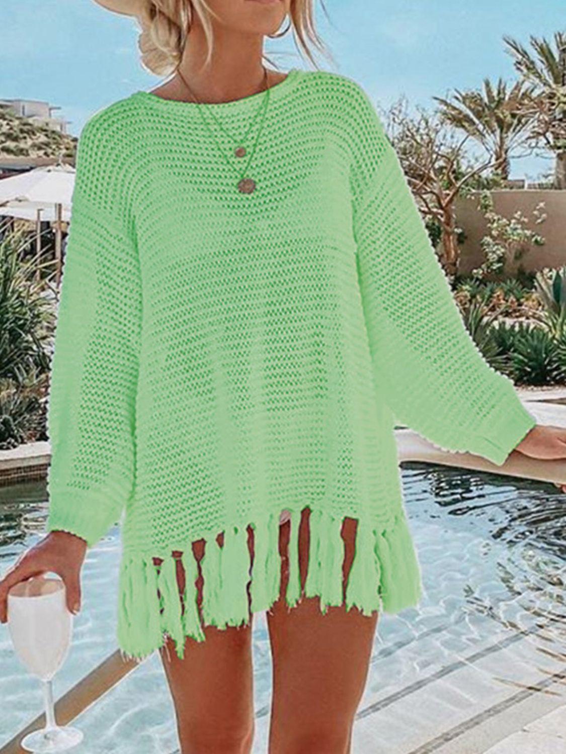 a woman standing next to a pool wearing a green sweater