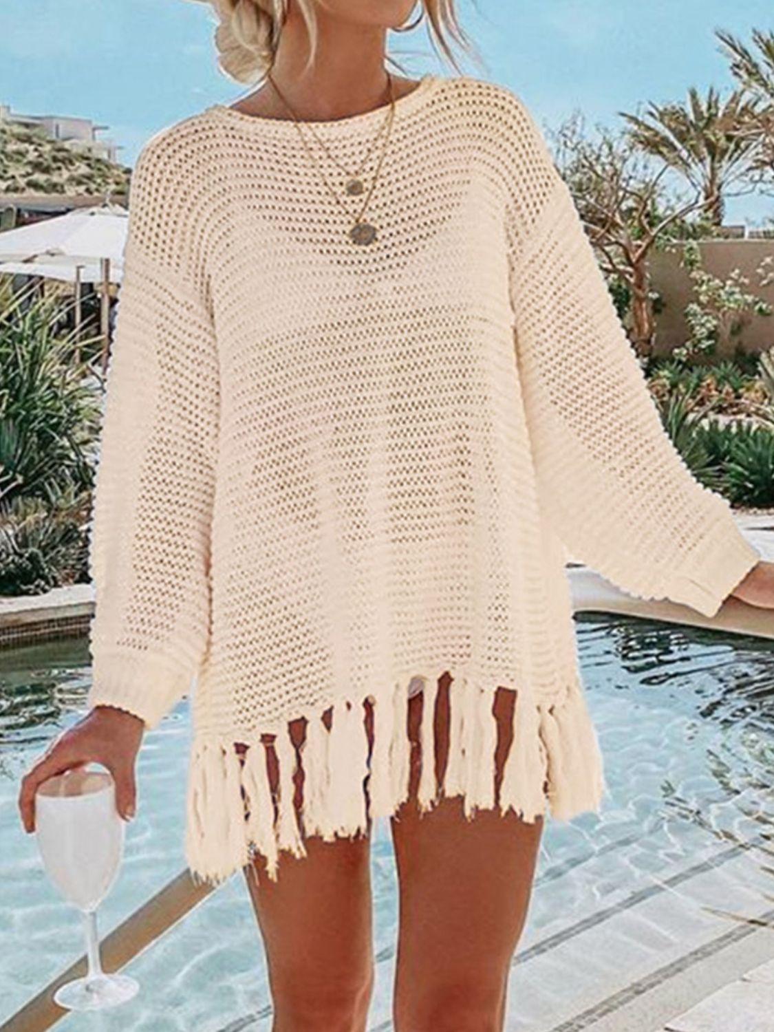 a woman standing next to a pool wearing a white sweater