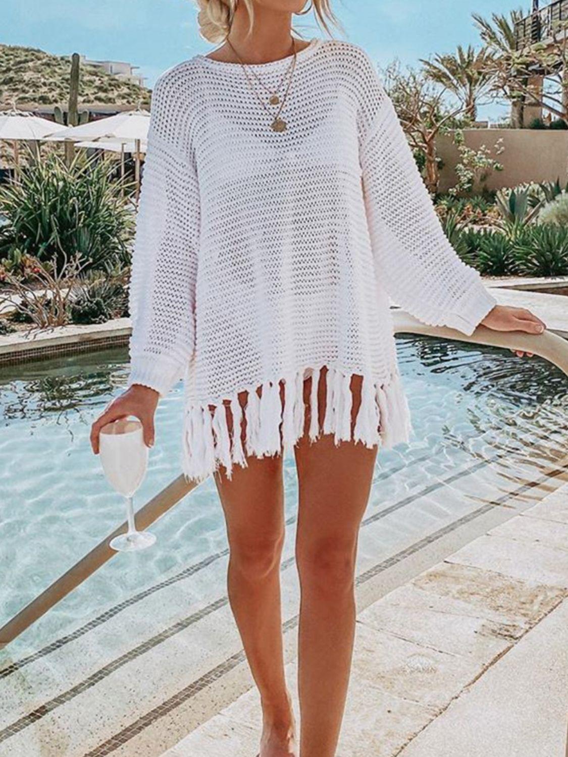 a woman standing next to a pool wearing a white sweater and shorts