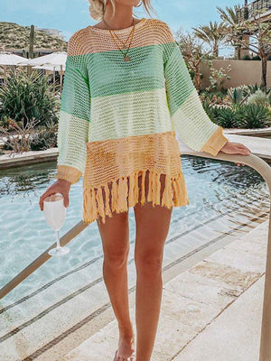 a woman standing next to a pool wearing a green and yellow sweater
