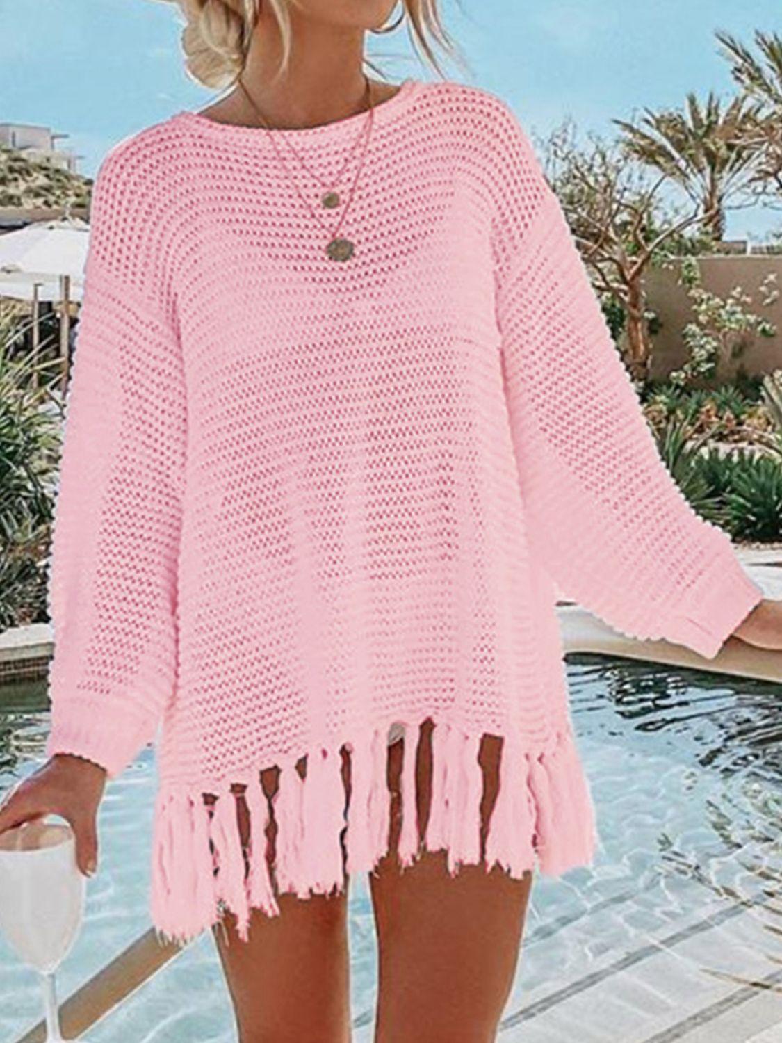 a woman standing next to a pool wearing a pink sweater