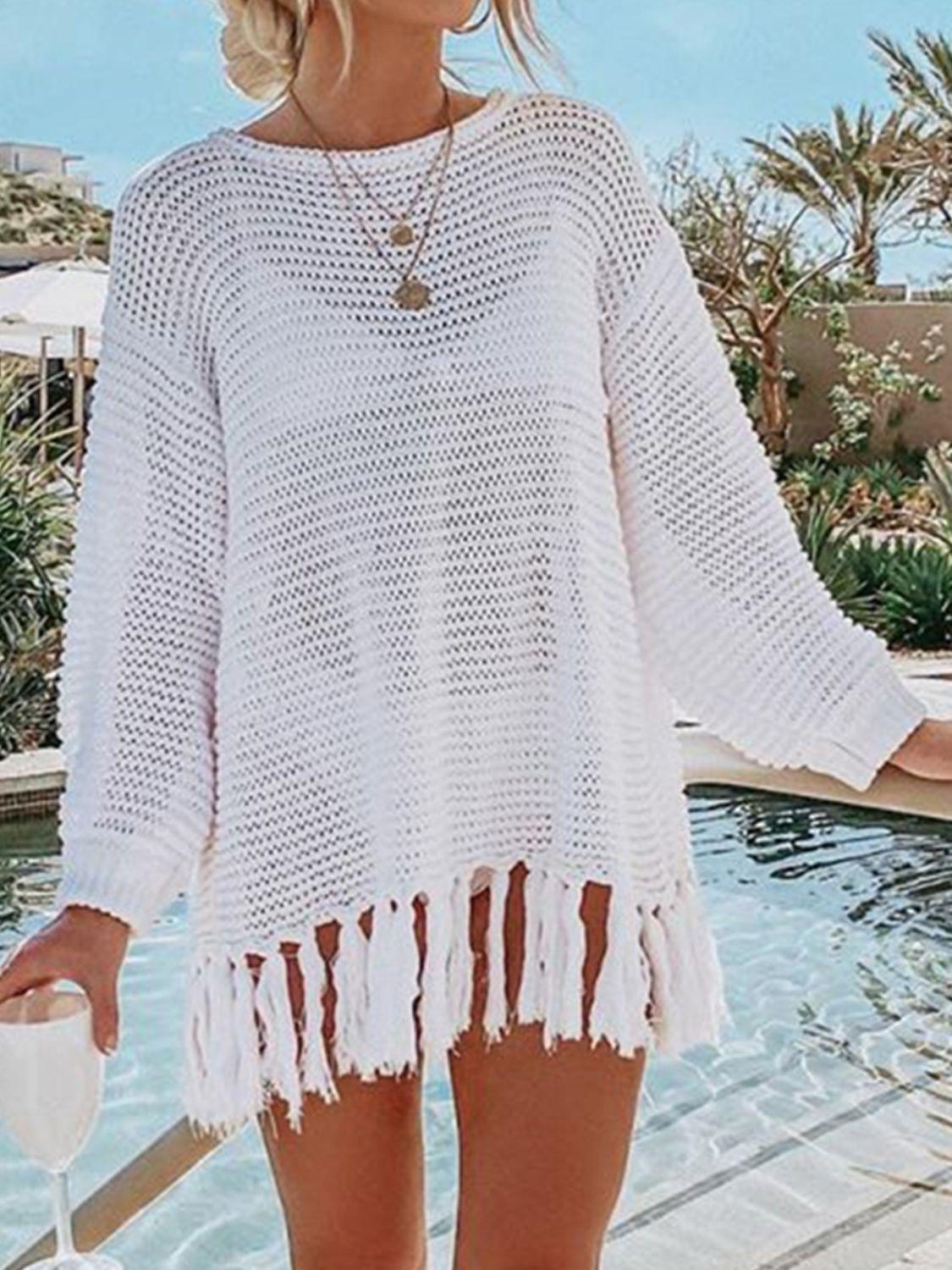 a woman standing next to a pool wearing a white sweater