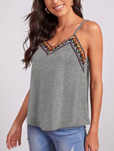 a woman wearing a grey top with a colorful design on it