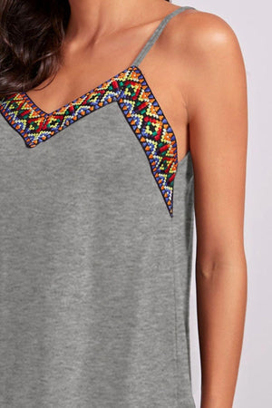 a woman wearing a grey top with a colorful design on it