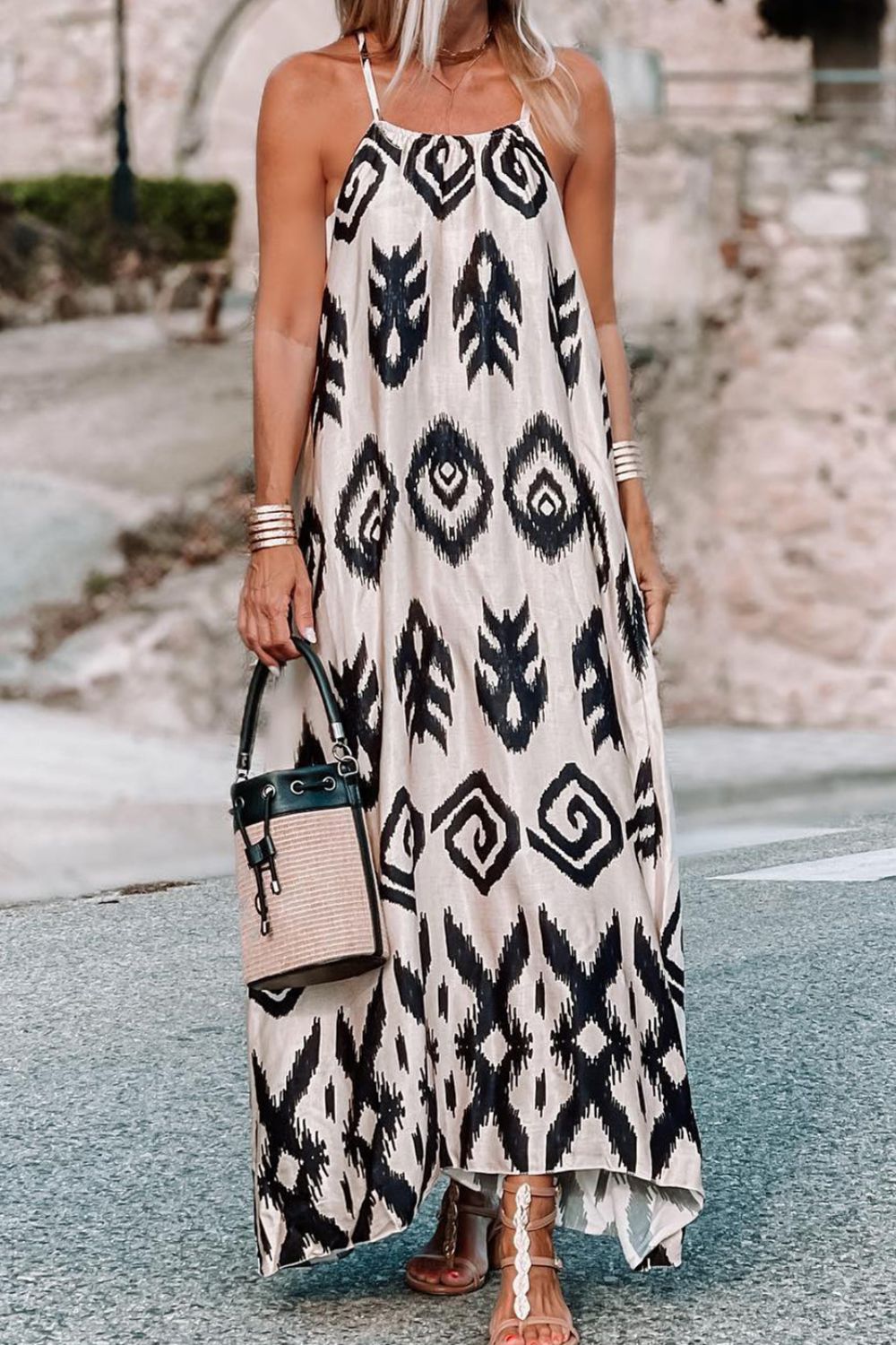 a woman in a black and white dress holding a handbag