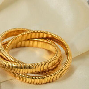 a close up of three gold rings on a white cloth