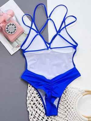 a blue and white one piece swimsuit next to a phone