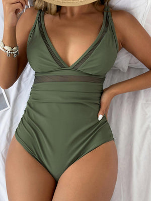 a woman in a green swimsuit laying on a bed