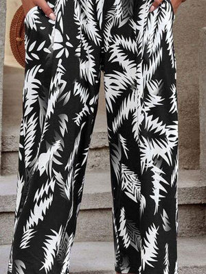 a woman wearing a black and white tropical print pants