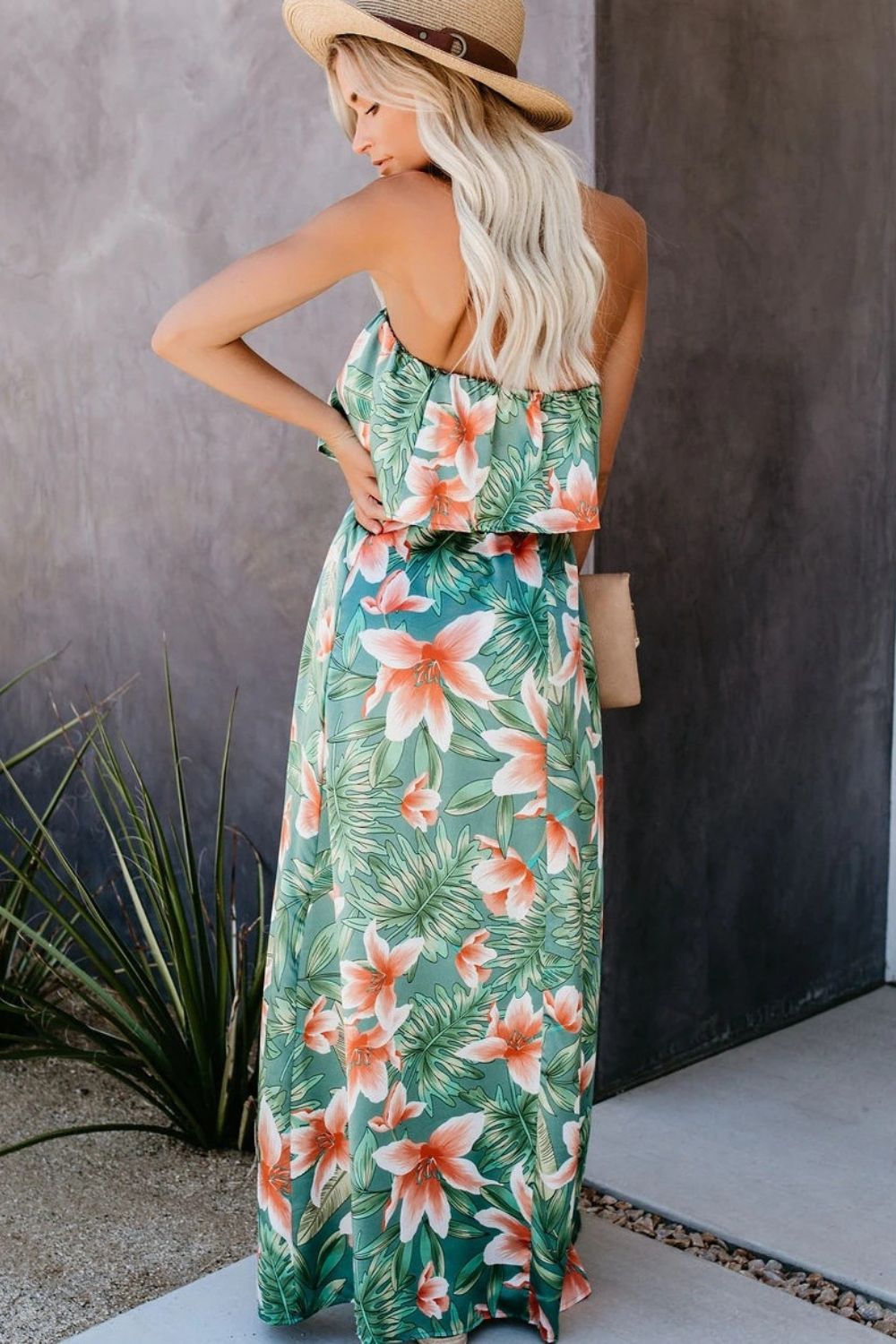 a woman wearing a tropical print dress and a straw hat