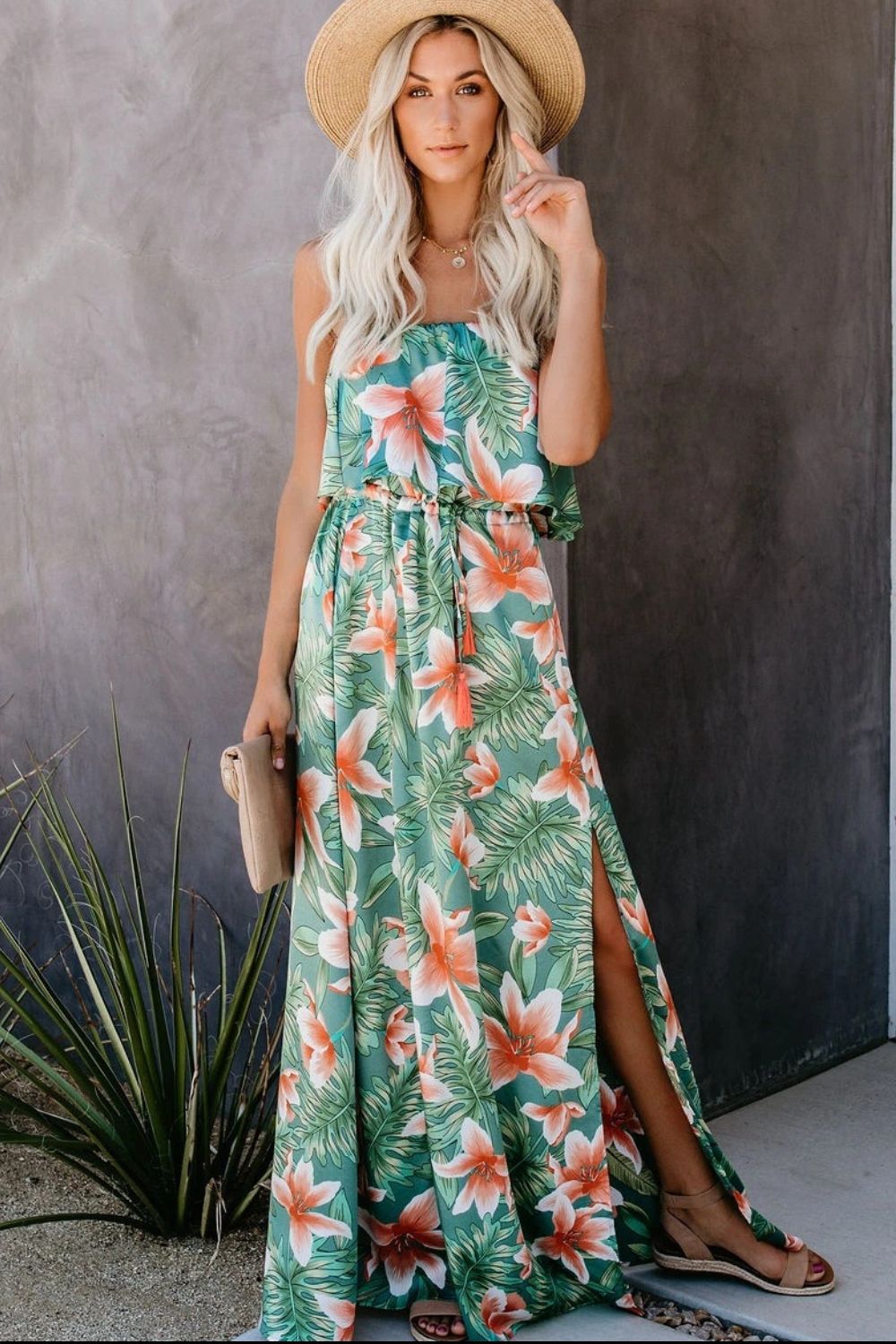 a woman wearing a green floral dress and a straw hat