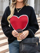 a woman holding a cup of coffee wearing a heart sweater