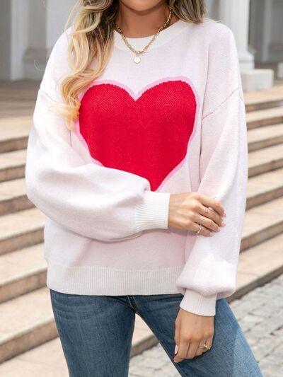 a woman wearing a white sweater with a red heart on it