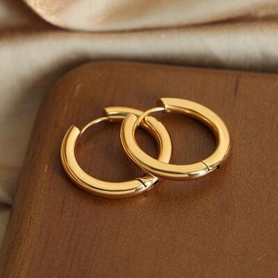 a pair of gold hoop earrings sitting on top of a wooden box