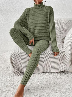 a woman sitting on a couch wearing a green sweater and pants