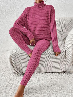 a woman sitting on a couch wearing a pink sweater and pants