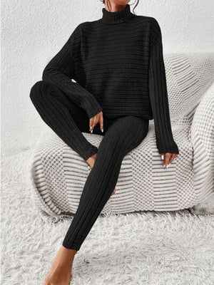 a woman sitting on a couch wearing a black turtle neck sweater and leggings