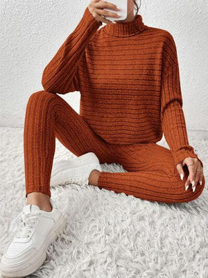 a woman sitting on the floor wearing an orange sweater and pants