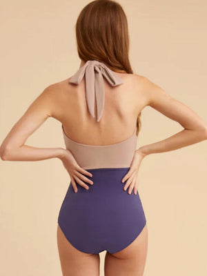 a woman in a purple and tan one piece swimsuit