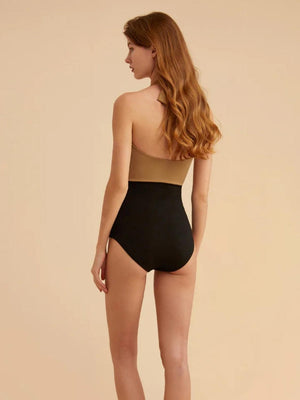 a woman in a black and tan one piece swimsuit