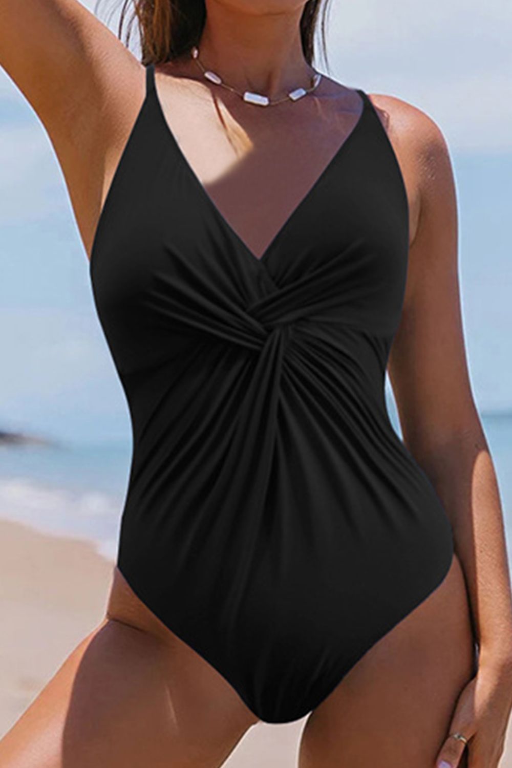 a woman in a black one piece swimsuit on the beach