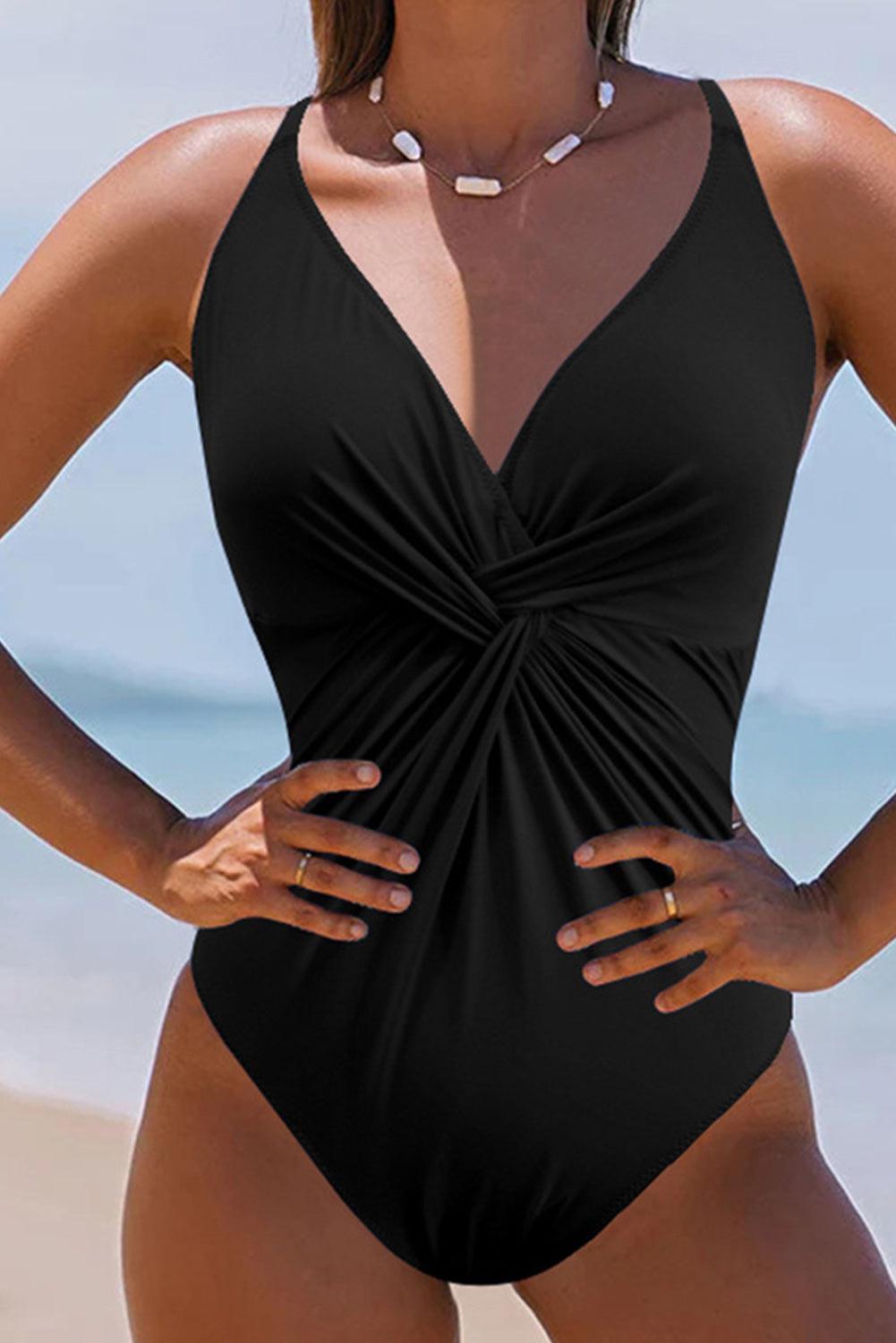 a woman in a black one piece swimsuit on the beach